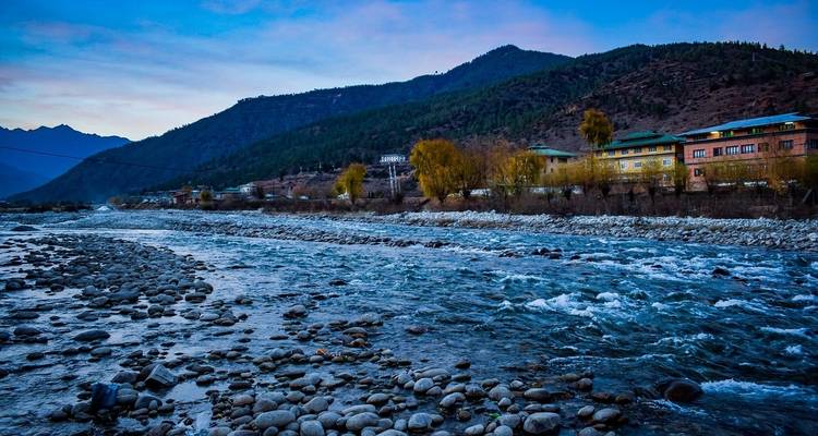 River flowing with mountainous landscape and buildings in the background.