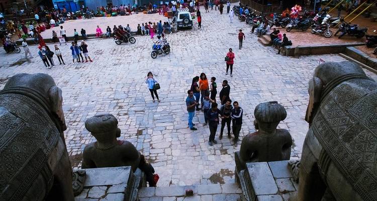View from above of a courtyard with people and stone statues.