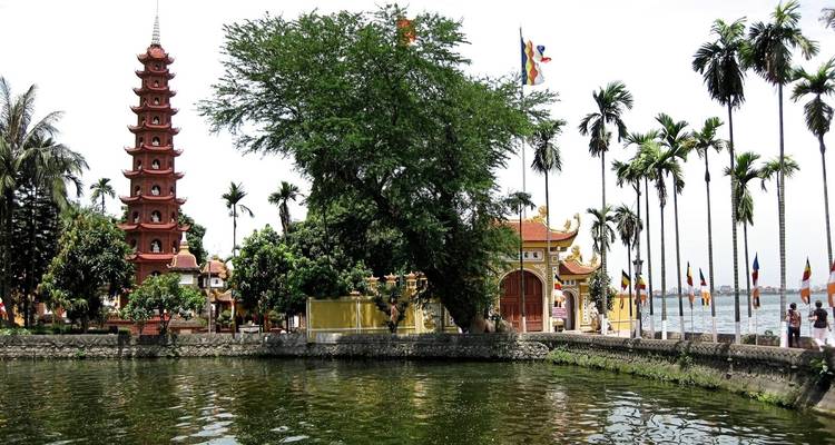 Temple et pagode au bord d'un lac entouré d'arbres.
