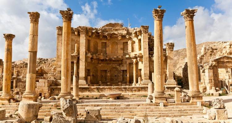 Ruins of a Roman amphitheater with columns under blue skies.