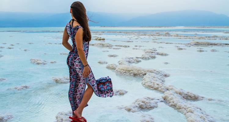 Woman standing on salt flats with mountains in the background.