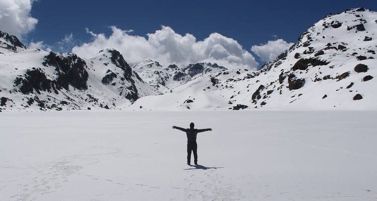 Person standing with arms outstretched on a snowy landscape.