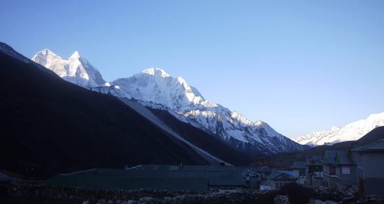 Panoramic view of snow-capped mountains with a small settlement in the foreground.