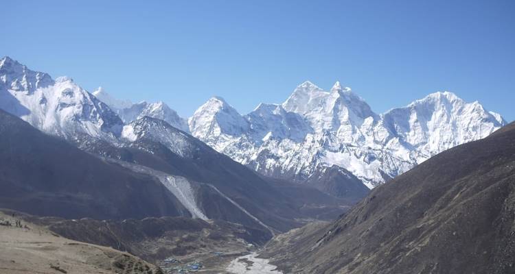 Wide view of mountains with snow on peaks under a clear blue sky.