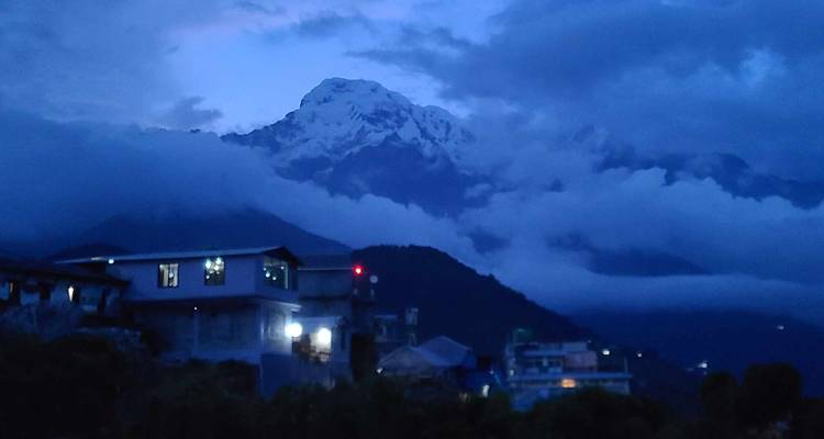 Mountain peak shrouded by clouds during evening twilight.