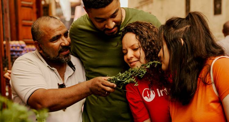 Groep mensen op een Marokkaanse markt die genieten van aromatische kruiden.