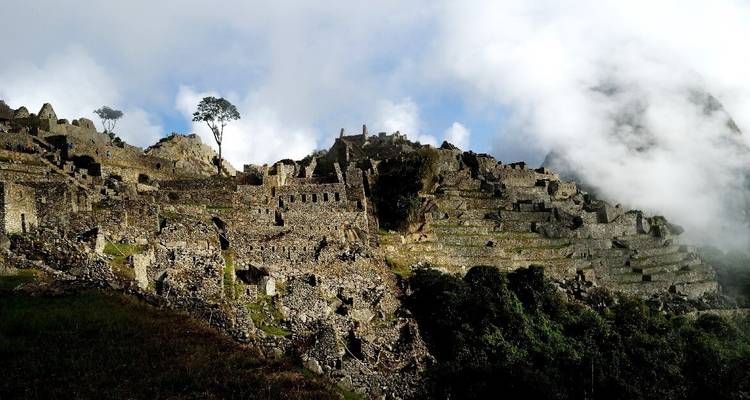 Machu Picchu ruins surrounded by mist and clouds.