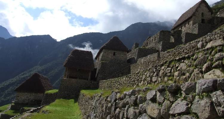 Stone buildings with thatched roofs on ancient terraces.