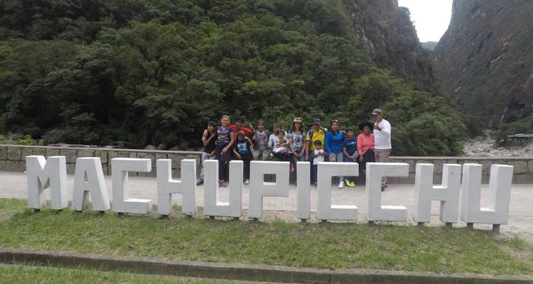 Group of tourists posing in front of Machu Picchu sign.
