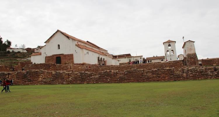 Large open courtyard with a church in the background and a few tourists.