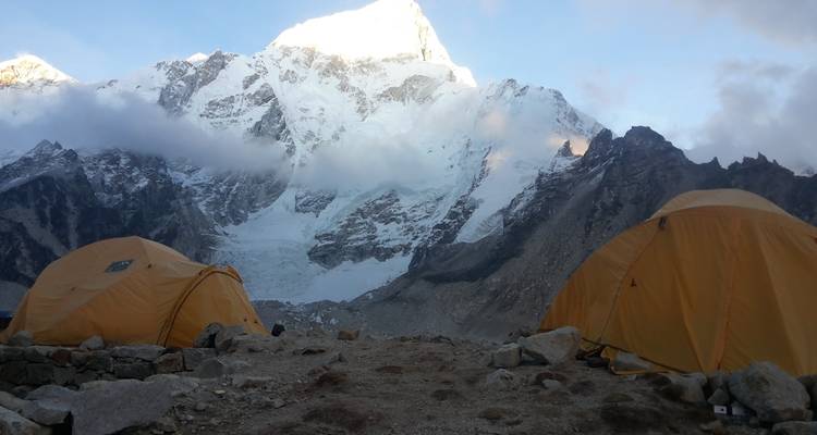 Tents in front of a wintry mountain at sunset.