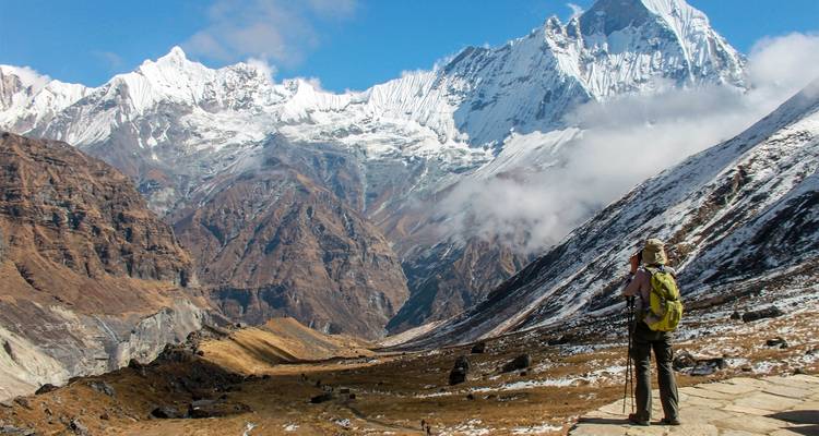 Solitary hiker gazing at snow-covered mountains.
