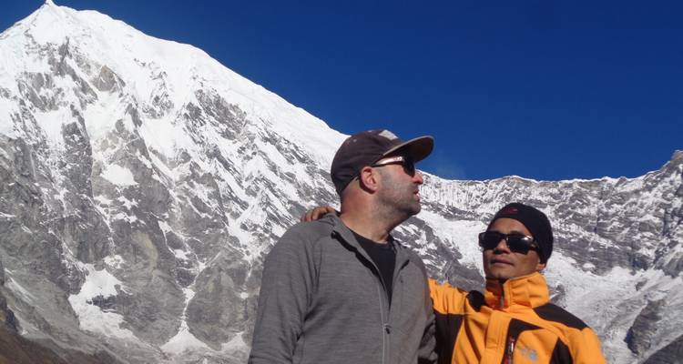 Twee toeristen staan voor met sneeuw bedekte bergen.