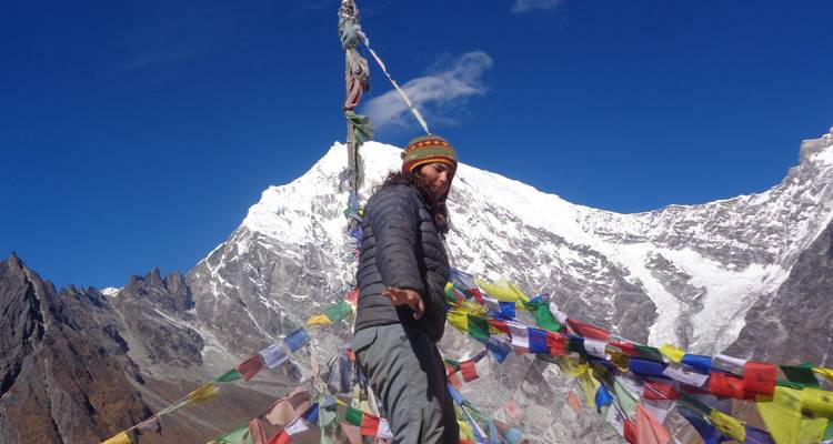 Toerist omringd door gebedsvlaggen in de bergen.