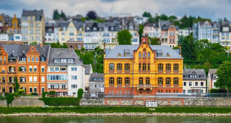 Mansiones coloridas a orillas del río a lo largo del Rin con un marcador de distancia visible en el malecón.