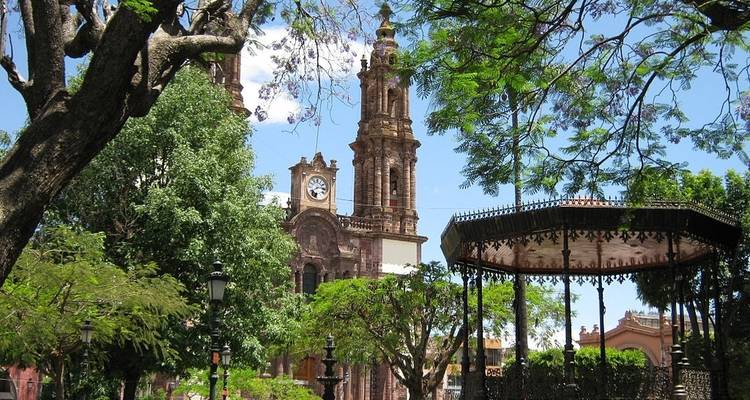 Una iglesia rodeada de árboles con una glorieta en primer plano.
