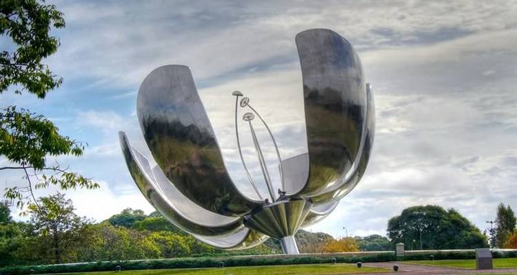 Metalen bloem sculptuur in een parkachtige omgeving.