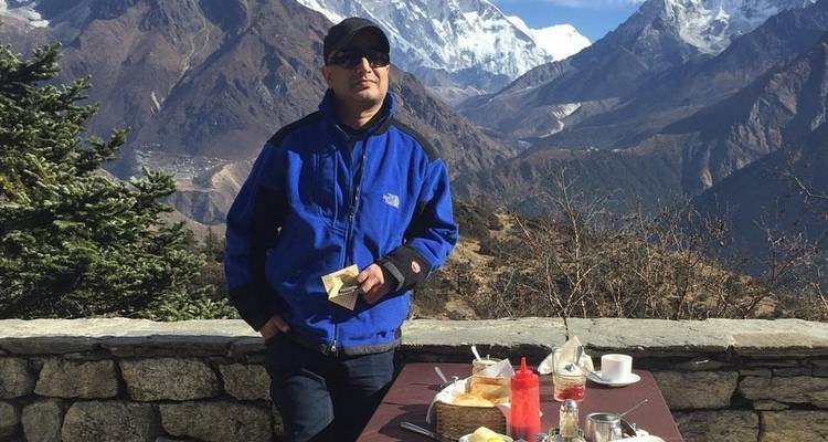 Ein Mann mit Bergen im Hintergrund, der im Freien eine Mahlzeit einnimmt.