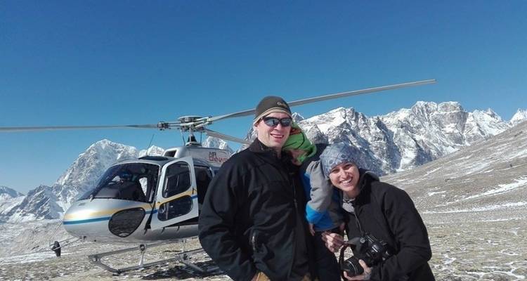 Eine Familie posiert vor einem Hubschrauber mit einer Bergkulisse.