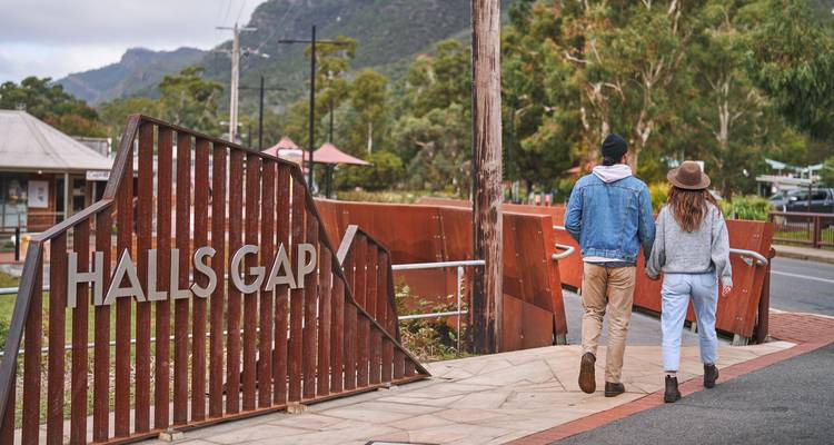 Stel wandelt langs het rustieke stalen bord dat bezoekers welkom heet in het plaatsje Halls Gap.