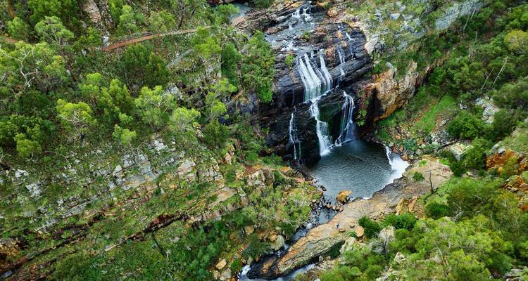 Luchtfoto van de meerlaagse MacKenzie Falls die in een diepe poel valt te midden van dicht bos.