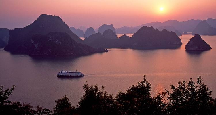 Atemberaubender malerischer Blick auf eine Kreuzfahrt bei Sonnenuntergang in einer Bucht mit Kalkstein-Karst.