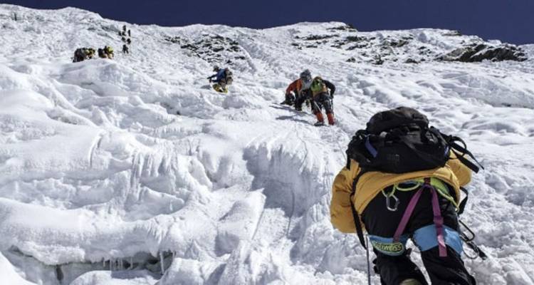 Climbers ascending a snowy and icy mountain path.