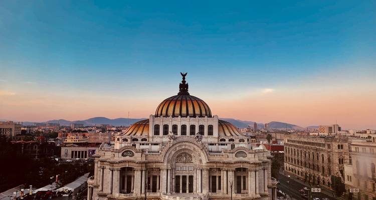 Vista del atardecer del Palacio de Bellas Artes con cúpula elevándose sobre el horizonte de la Ciudad de México.
