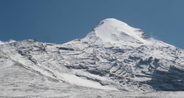 Jagged snow-covered mountain peak under clear blue skies.