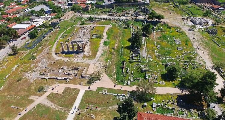 Ancient ruins with columns in a green field.