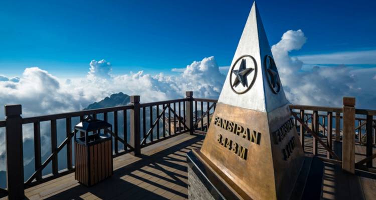 Fansipan topmarkering tegen een achtergrond van wolken en blauwe lucht.