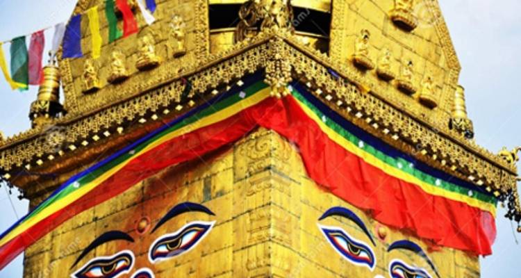 Goldene Stupa mit dekorativen Flaggen vor blauem Himmel.