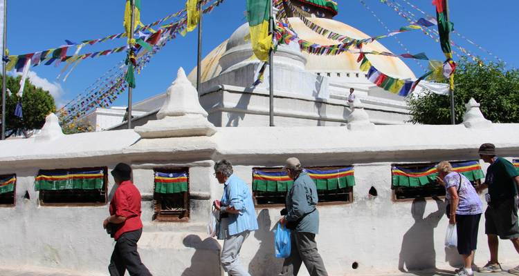 Menschen, die um eine Stupa mit Gebetsfahnen herumgehen.