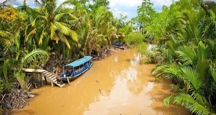 Kanalblick im Mekong-Delta mit Booten und dichter Vegetation.