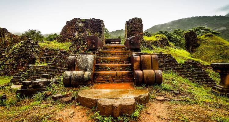 Las antiguas ruinas de ladrillos cubiertos de musgo y los escalones de piedra del Santuario de My Son rodeados de selva.