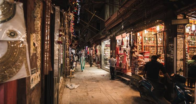 Belebte Gasse in Kathmandu mit Geschäften und Menschen.