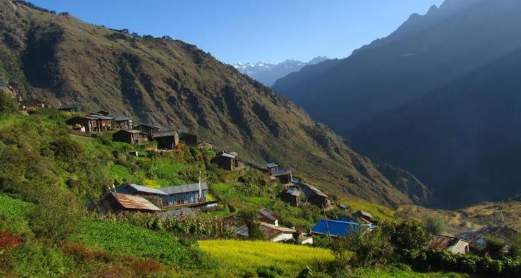 Nepalesisches Bergdorf unter einem klaren blauen Himmel mit fernen Bergen.
