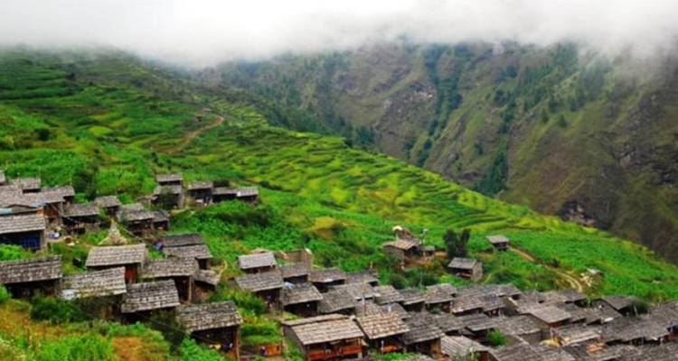 Terrassenfelder in einem Tal in Nepal mit traditionellen Häusern.
