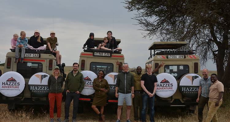 Eine Gruppe von Menschen und Safarifahrzeugen in der Savanne.