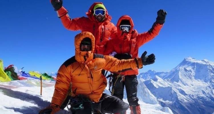 Drie bergbeklimmers die vieren op een besneeuwde top.