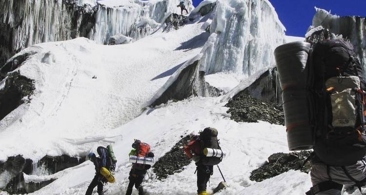 Bergbeklimmers die trekken door een besneewd landschap met ijzige rotswanden.