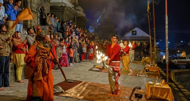A night scene of a religious ceremony with people and flames.