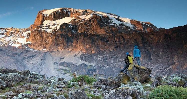 Zwei Wanderer bewundern einen schneebedeckten Berg in der Ferne.