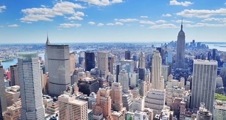 Vue aérienne lumineuse de jour des gratte-ciel de Midtown Manhattan sous un ciel bleu éclatant avec des nuages épars.
