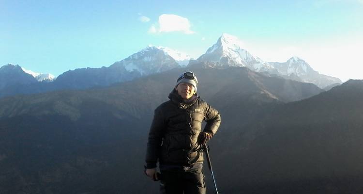 Persoon die poseert met een uitzicht op besneeuwde bergen op de achtergrond.