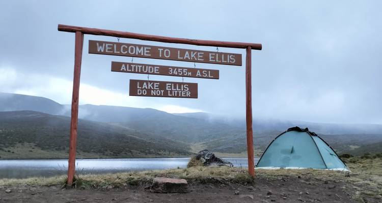 Una vista del lago con una tienda de campaña y un letrero que indica 'Bienvenidos al Lago Ellis'.