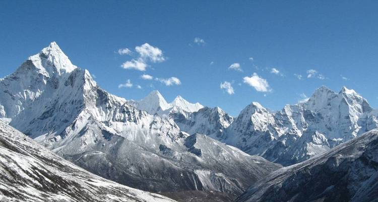 Panoramisch uitzicht op een besneeuwde bergketen onder een heldere hemel.