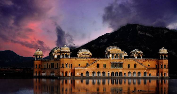 Palais Jal Mahal à Jaipur, Inde, avec un lac réfléchissant, sur fond de ciel au coucher du soleil.
