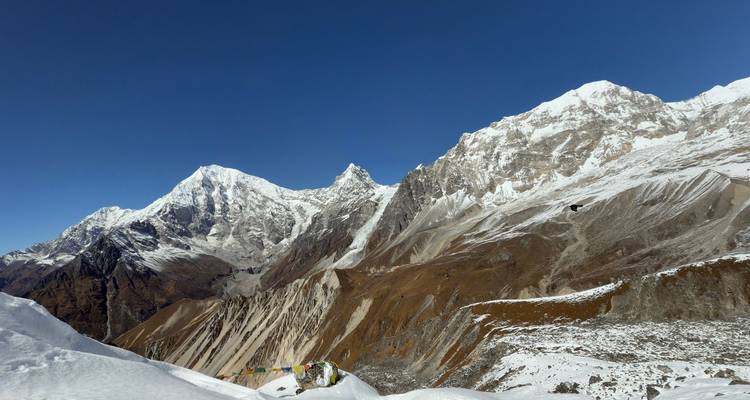 Imposante Himalaya-toppen rijzen uit boven een mengeling van sneeuw en roestkleurige bergkammen onder kristalhelder blauwe hemels.