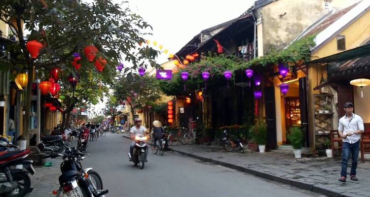 Una calle con faroles coloridos y un motociclista.